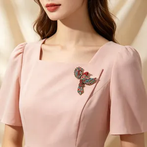 Detailansicht einer Vintage-Brosche mit bunten Strasssteinen in Vogelform auf rosa.