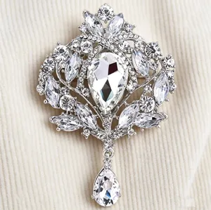 Vue détaillée d'une broche couronne vintage avec des strass blancs et un pendentif goutte