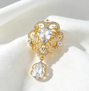 Detailed macro view of a vintage palace-style gold brooch with crystals on white silk.