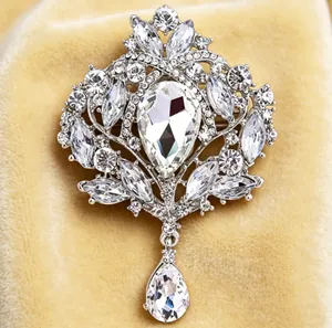 Détail rapproché d'une broche couronne en cristal argenté vintage avec pendentif.