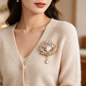 Élégante broche vintage en forme de couronne avec cristaux blancs sur un cardigan beige.