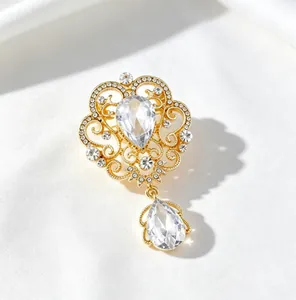 Detailed view of an elegant gold royal crown brooch decorated with sparkling teardrop crystals.