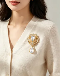 Detail of vintage gold crown brooch featuring sparkling teardrop crystals on a beige cardigan
