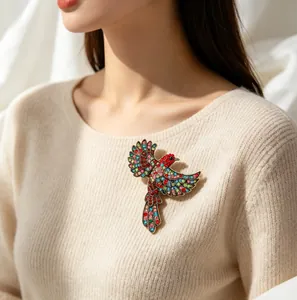 Nahaufnahme einer bunten Strass-Elsternbrosche auf einem cremefarbenen Pullover.
