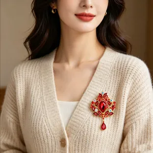 Vue détaillée d'une broche couronne vintage avec cristaux rouges sur un gilet beige.