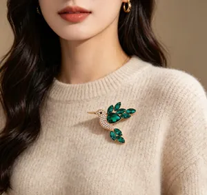 Detailed view of an elegant emerald green crystal hummingbird brooch on a sweater