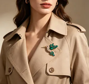 Detailed view of elegant green rhinestone hummingbird brooch pinned on a beige trench coat