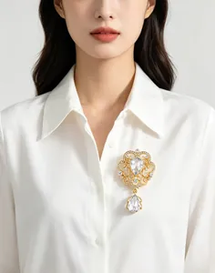 Close-up of an exquisite palace style crown brooch with water drop crystals on a white shirt.