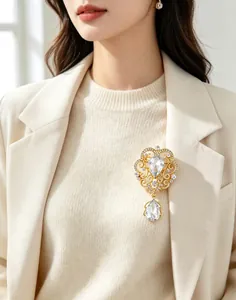 Elegant vintage gold crown brooch with sparkling crystals and teardrop pendant on blazer