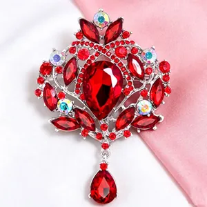 Détail d'une broche couronne vintage avec des cristaux rouges et irisés sur de la soie