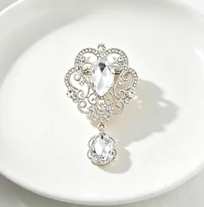 Close-up detail of a vintage court style silver brooch with clear teardrop crystals