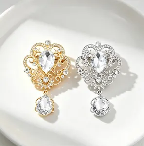Close-up view of ornate gold and silver palace style brooches with pear-shaped crystals