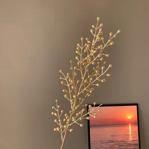Gros plan d'une branche de baies artificielles dorées pour des décors de Nouvel An.