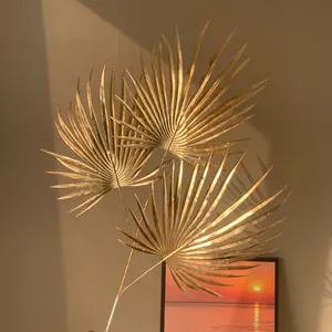 Détail rapproché de feuilles de palmier artificielles dorées sous une lumière naturelle