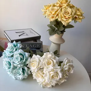 Close-up of white and blue artificial silk roses with decorative books and vase display