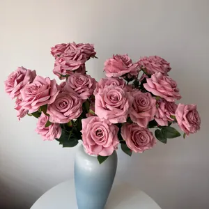 Detail view of dusty pink artificial roses with lifelike water droplets in a blue vase.