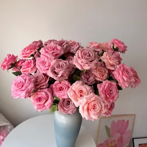 Close-up detail of artificial pink roses with realistic water drops in a blue elegant vase.