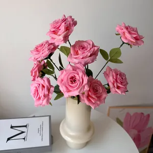 Realistic pink artificial roses with water droplets in a cream vase for home decor