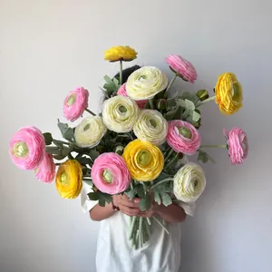Person holding a large bouquet of colorful artificial ranunculus flowers for home decor