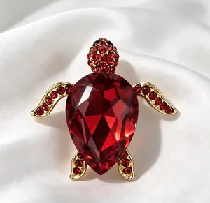 Gros plan détaillé d'une broche tortue dorée ornée de cristaux rouges facettés.