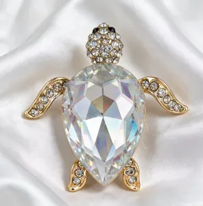 Détail d'une broche tortue en or avec un grand cristal irisé et des pierres pavées.