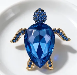 Gros plan sur la carapace en cristal bleu facetté et les détails en strass de la broche tortue