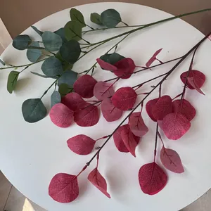 Detailopname van kunstmatige groene en bordeauxrode eucalyptusbladeren op witte tafel