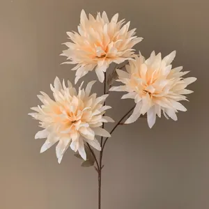 Gros plan de trois magnifiques chrysanthèmes artificiels orange pâle sur une tige