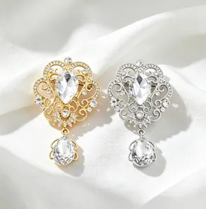 Detailed view of exquisite gold and silver crown brooches with teardrop crystal pendants