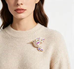 Close-up of iridescent hummingbird brooch pinned on a beige knitted sweater.