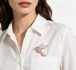 Detail view of a vibrant hummingbird brooch with colorful crystals on a white shirt.