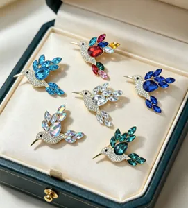 Detailed macro view of six hummingbird brooches with vibrant rhinestones in a box.