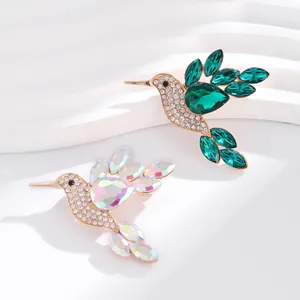 Detailed view of two elegant hummingbird brooches with sparkling green and iridescent gems.