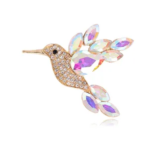 Detailed view of sparkling crystal hummingbird brooch with iridescent stones and gold finish