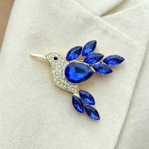 Detail shot of a sparkling blue hummingbird brooch with intricate rhinestone accents.