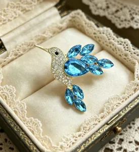 Detail of a golden hummingbird brooch with blue crystals in a lace jewelry box