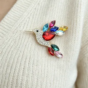 Elegant colorful hummingbird brooch with sparkling rhinestones pinned on cream knit sweater.