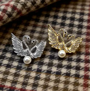Vista detallada de exquisitos broches de doble cisne con diamantes de imitación y perlas