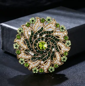 Detailed view of a vintage luxury brooch with green rhinestones in a floral wreath design.