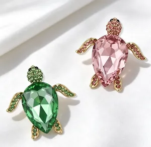 Détail des broches tortues de luxe serties de cristaux en couleurs vert et rose élégantes