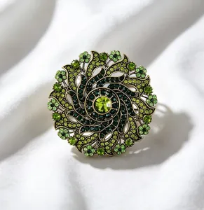 Detailed view of a vintage luxury green rhinestone rotating wreath brooch on silk