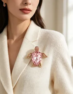 Vue détaillée d'une élégante broche tortue en strass rose sur un pull blanc chic