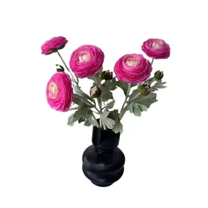 Artificial pink Ranunculus bouquet with green leaves in a black textured vase for decor