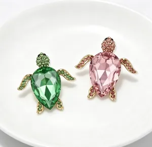 Vue détaillée de deux broches de tortue avec des cristaux étincelants verts et roses