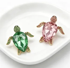 Vue détaillée de deux broches tortue incrustées de cristaux en vert et rose