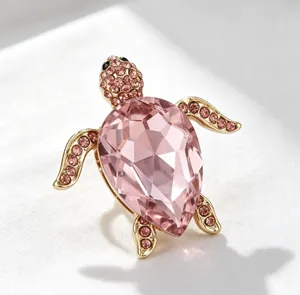 Gros plan détaillé d'une élégante broche tortue en cristal rose avec monture dorée