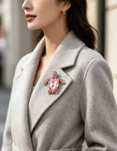 Vue détaillée d'une élégante broche tortue en cristal rose sur un revers de manteau gris.