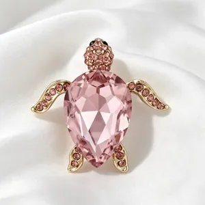 Broche tortue de mer en cristal rose et plaqué or sur fond de soie blanche élégante