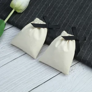 Détail de pochettes en coton crème avec un élégant nœud en ruban noir pour les bijoux