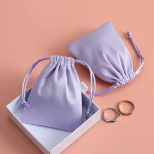 Primer plano de bolsas de franela lila con cordón para guardar joyas y pintalabios